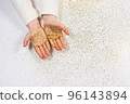 Child's hands holding golden glitter on sparkling white background. 96143894