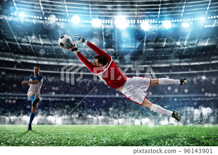 Goalkeeper catches the ball in the stadium during a football game. Goalkeeper catches the ball in the stadium during a football game. 96143901