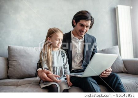 Happy little girl watching a movie on the computer with her father Happy little girl watching a movie on the computer with her father 96143955