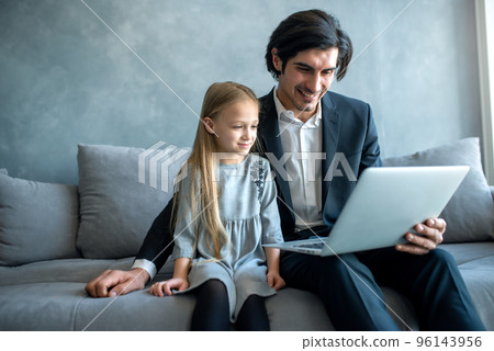 Happy little girl watching a movie on the computer with her father Happy little girl watching a movie on the computer with her father 96143956