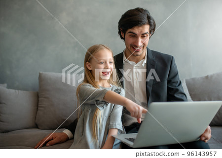 Happy little girl watching a movie on the computer with her father Happy little girl watching a movie on the computer with her father 96143957