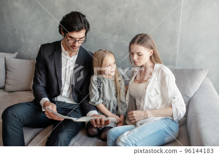 Happy little girl reads a book with her parents Happy little girl reads a book with her parents 96144183