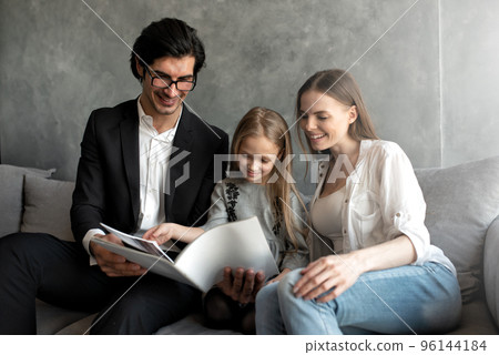 Happy little girl reads a book with her parents Happy little girl reads a book with her parents 96144184