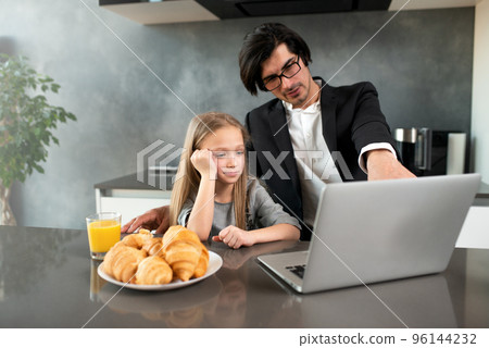 Happy little girl watching a movie on the computer with her father 96144232