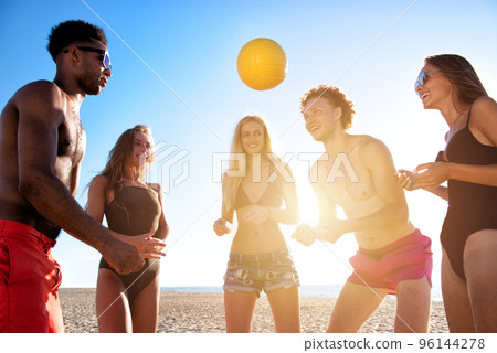 Group of friends playing at beach volley at the beach 96144278