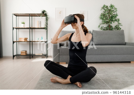 Woman in VR headset doing fitness Woman in VR headset doing fitness 96144318