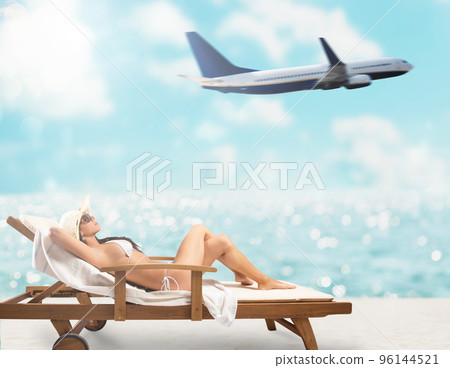 Beautiful girl sitting on a deck chair at the beach at sunset with airplane on background Beautiful girl sitting on a deck chair at the beach at sunset with airplane on background 96144521