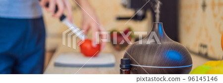 BANNER, LONG FORMAT A man prepares food next to an aroma diffuser. cook cuts ripe red peppers in the kitchen. Cooking fresh, ripe, bell pepper salad for guests. Summer fresh vegetable salad BANNER, LONG FORMAT A man prepares food next to an aroma diffuser. cook cuts ripe red peppers in the kitchen. Cooking fresh, ripe, bell pepper salad for guests. Summer fresh vegetable salad 96145146
