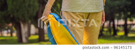 BANNER, LONG FORMAT A man holds a Ukrainian flag in his hands. concept Ukrainian patriot, rally in support of Ukraine Portrait of a disgruntled girl sitting at a cafe table BANNER, LONG FORMAT A man holds a Ukrainian flag in his hands. concept Ukrainian patriot, rally in support of Ukraine Portrait of a disgruntled girl sitting at a cafe table 96145173