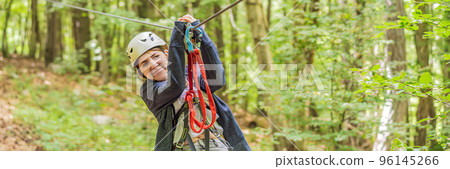 BANNER, LONG FORMAT Happy women girl female gliding climbing in extreme road trolley zipline in forest on carabiner safety link on tree to tree top rope adventure park. Family weekend children kids 96145266