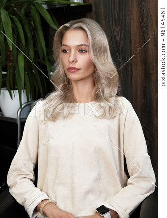 Young woman in a hairdressing salon dyes her hair blond 96145461