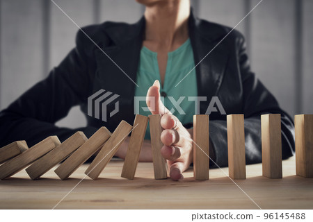 Businesswoman stops a chain fall like domino game. Concept of preventing crisis and failure in business. 96145488