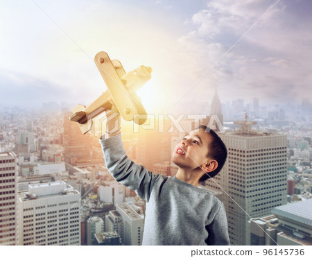 Kid plays with a wooden toy airplane 96145736