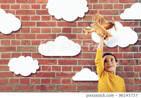 Kid plays with a wooden toy airplane 96145737