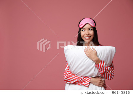 Beautiful Asian woman with pillow on dusty rose background, space for text. Bedtime 96145816