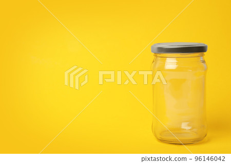 Closed empty glass jar on yellow background, space for text Closed empty glass jar on yellow background, space for text 96146042