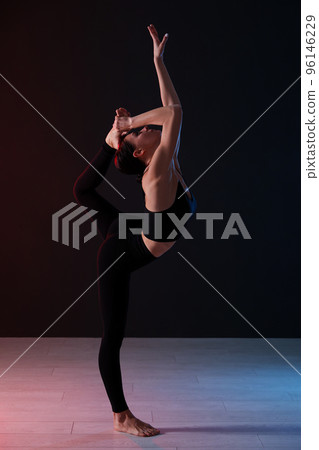 Young professional acrobat exercising in dark studio 96146229