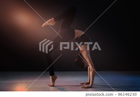 Young professional acrobat exercising in dark studio 96146230
