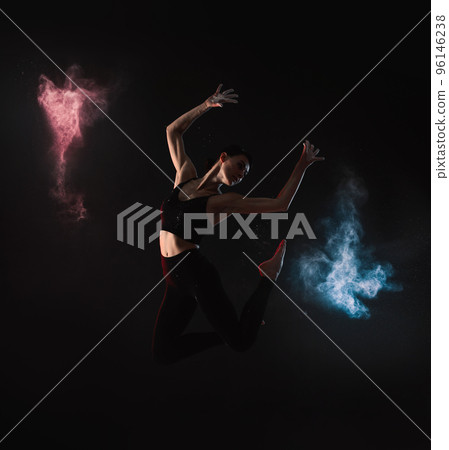 Professional acrobat with chalk powder exercising in dark studio 96146238