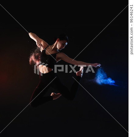 Professional acrobat with chalk powder exercising in dark studio 96146241