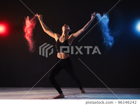 Professional acrobat with chalk powder exercising in dark studio 96146242