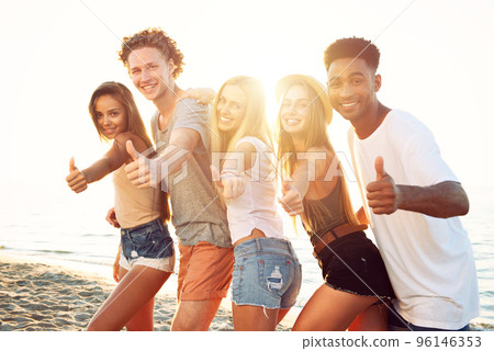 Group of happy friends having fun at ocean beach at dawn 96146353