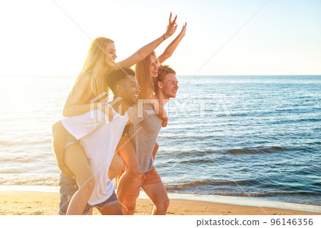 Happy smiling couples playing at the beach 96146356