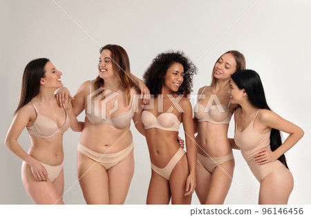 Group of women with different body types in jeans and underwear taking selfie against light 96146456