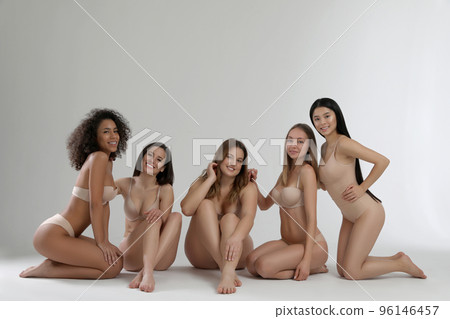 Group of women with different body types in jeans and underwear taking selfie against light 96146457