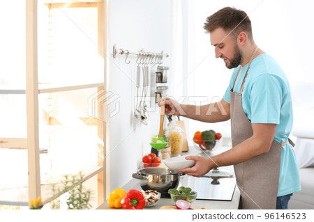 Young man pouring delicious soup into bowl at home 96146523