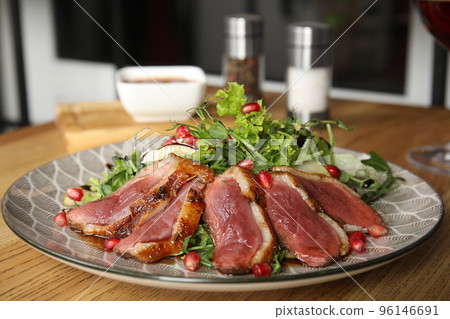 Delicious salad with roasted duck breast served on wooden table indoors 96146691