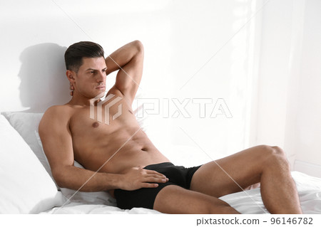 Handsome man in black underwear on bed indoors 96146782