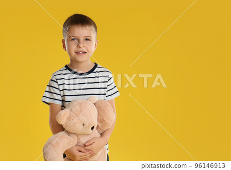 Little boy with toy bear on yellow background. Space for text 96146913