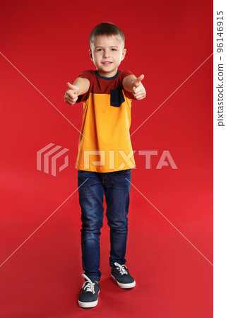 Little boy showing thumbs up on red background 96146915