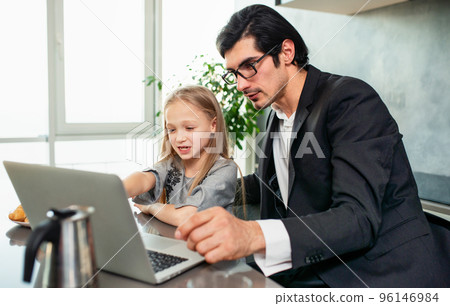 Happy little girl watching a movie on the computer with her father Happy little girl watching a movie on the computer with her father 96146984