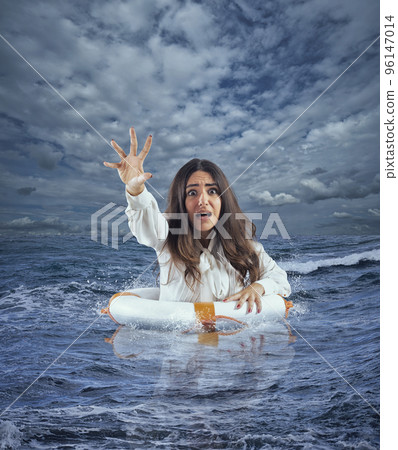 Businesswoman in the ocean with lifebelt asks help during a storm 96147014