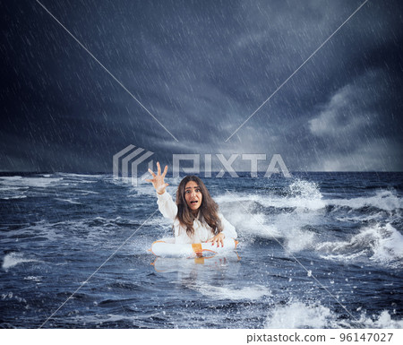 Businesswoman in the ocean with lifebelt asks help during a storm 96147027