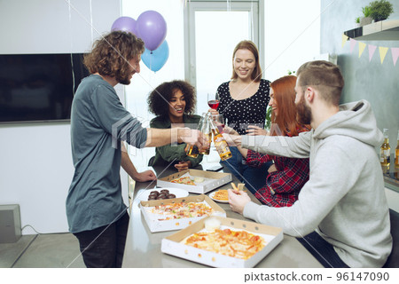 Young friends eat pizza and drink beer having fun together at home. 96147090
