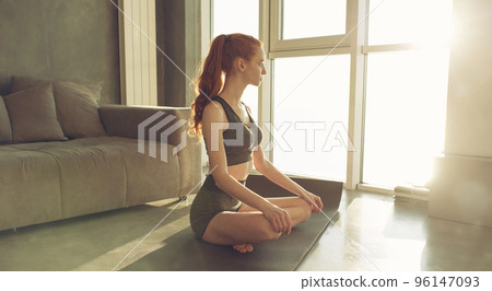 Young girl relaxing in yoga position at home Young girl relaxing in yoga position at home 96147093