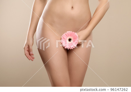 Woman with gerbera showing smooth skin on beige background, closeup. Brazilian bikini epilation 96147262