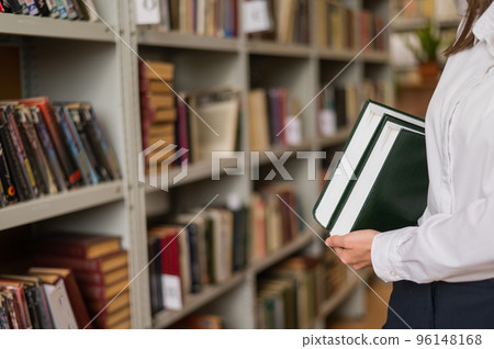 Close-up of female hands with books in public library.  96148168