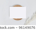 Greeting card or invitation card with white dry flower leaves on wood plate or tray in white background, top view mock up for design 96149076