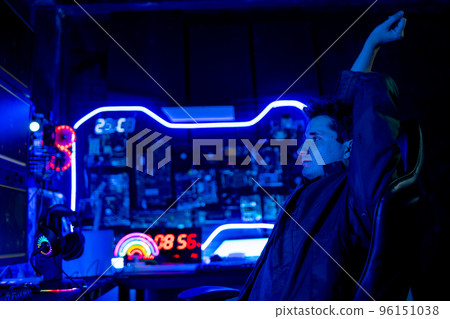 Gamer man do stretching for his arms and sit on chair look at monitor during streaming game Gamer man do stretching for his arms and sit on chair look at monitor during streaming game 96151038