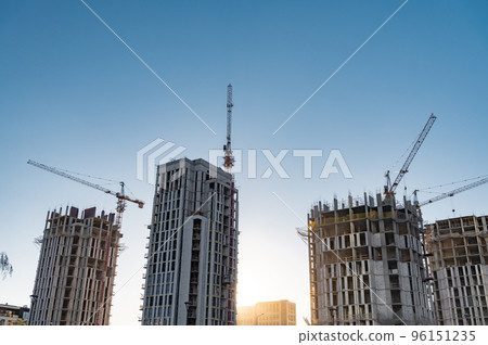 Tall buildings under construction and cranes under a blue sky Tall buildings under construction and cranes under a blue sky 96151235