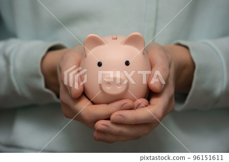 Women's hands hold a piggy bank close-up. 96151611