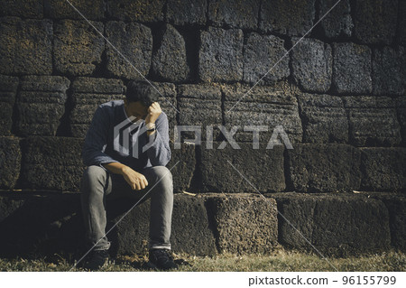 Asia you man sitting alone.He sitting alone beside old wall.man very sad and depressed. 96155799
