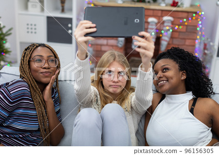 A crazy selfie of African and European friends, right by the Christmas fireplace. 96156305