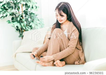 Japanese woman cutting her toenails on the sofa at home Japanese woman cutting her toenails on the sofa at home 96156501