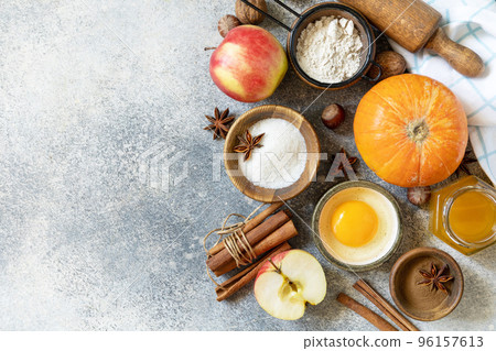 Baking food background. Pumpkins, apples, honey, nuts and seasonal spices for pumpkin or apple pie on a gray tabletop. View from above. Copy space. Baking food background. Pumpkins, apples, honey, nuts and seasonal spices for pumpkin or apple pie on a gray tabletop. View from above. Copy space. 96157613