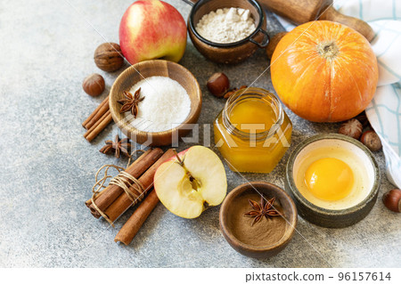 Baking food background. Pumpkins, apples, honey, nuts and seasonal spices for pumpkin or apple pie on a gray tabletop. Copy space. Baking food background. Pumpkins, apples, honey, nuts and seasonal spices for pumpkin or apple pie on a gray tabletop. Copy space. 96157614